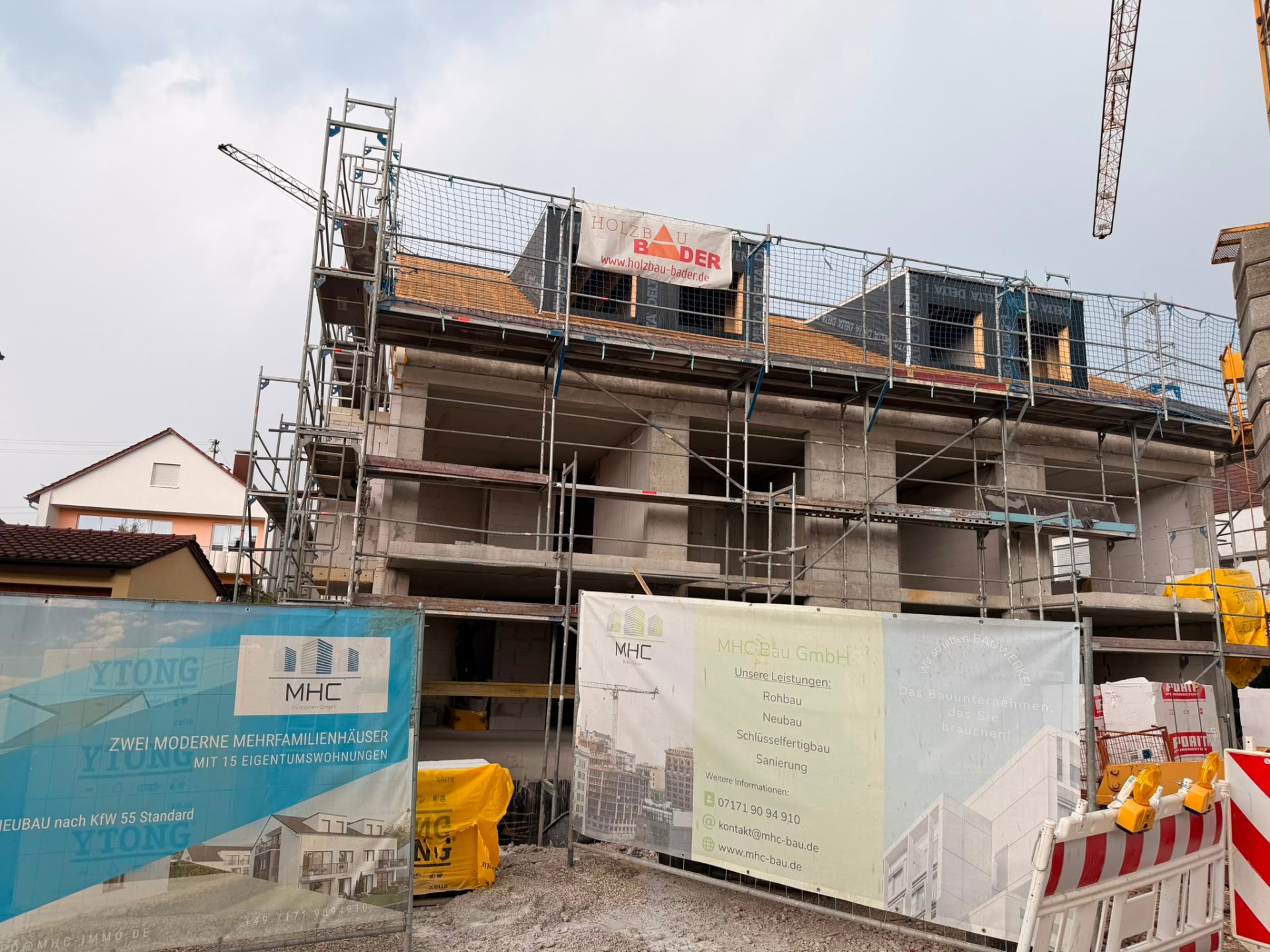 Frontfassade des Neubauprojekts mit MHC-Bauschild